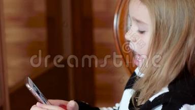 可爱的小女孩玩手机，女孩打开手机上的应用程序，玩手机游戏，说话